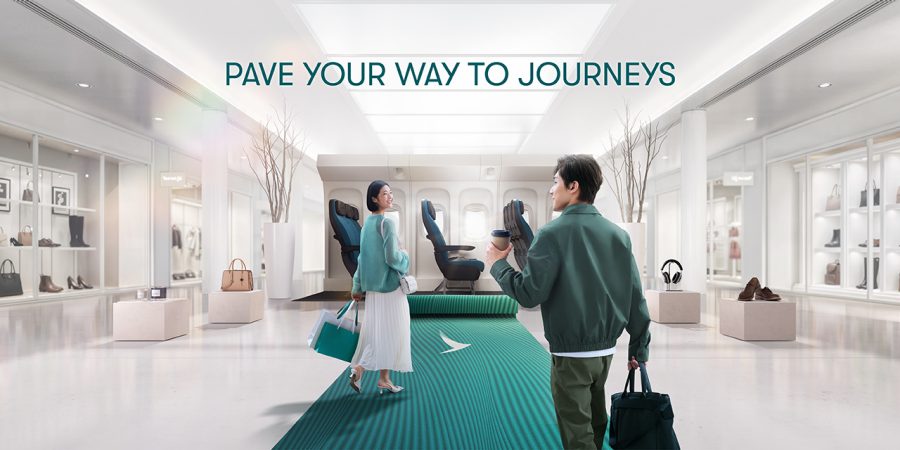 A modern, well-lit hallway with two people walking on a green carpet, surrounded by luxury display cases featuring handbags and shoes.